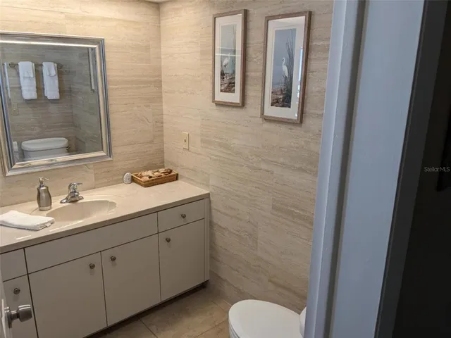a bathroom with a granite countertop toilet sink and mirror
