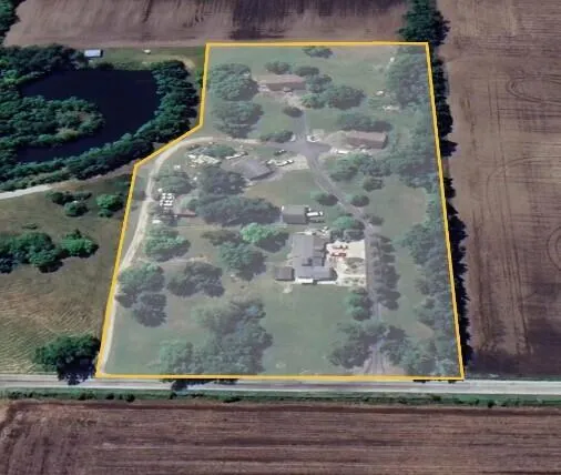 an aerial view of a residential houses with outdoor space and trees all around