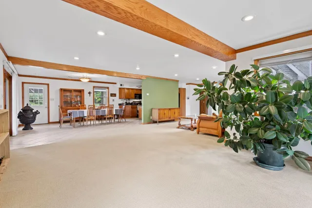 a kitchen with stainless steel appliances granite countertop a stove top oven a sink a dining table and chairs with wooden floor