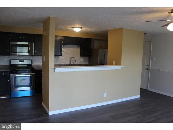 a view of kitchen with stainless steel appliances wooden floor and cabinets