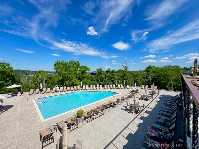 a view of a swimming pool with lawn chairs and potted plants