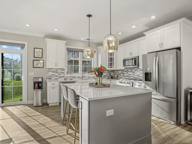 a kitchen with stainless steel appliances granite countertop a sink a stove a refrigerator and island with wooden floor