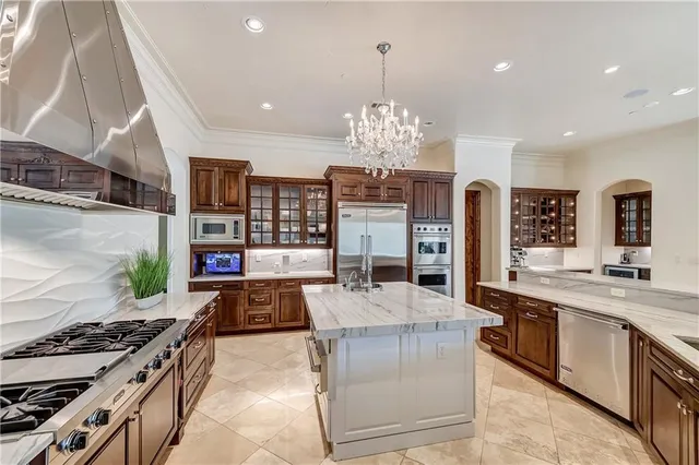 a large kitchen with stainless steel appliances granite countertop a stove and a view of living room