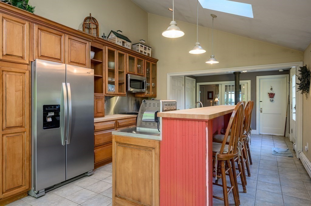 34 Clapp Street Abington, MA 02351 - Photo 7 of 21 a kitchen with stainless steel appliances kitchen island granite countertop a refrigerator a stove a sink a dining table and chairs with wooden floor