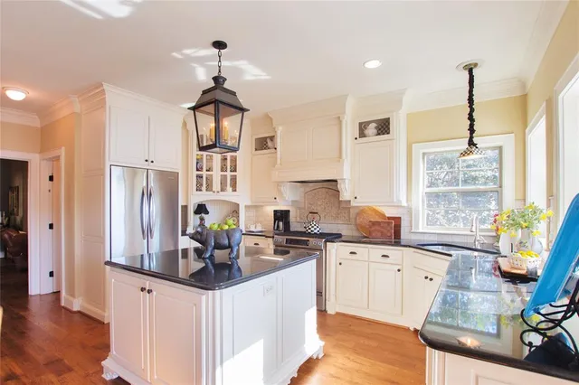 a kitchen with stainless steel appliances granite countertop a sink dishwasher a refrigerator and cabinets with wooden floor