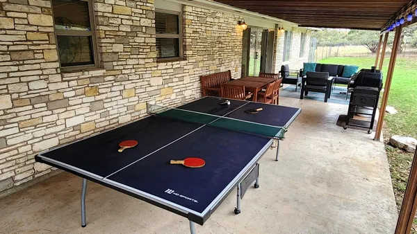 a view of a patio with table and chairs and couches with wooden floor and fence