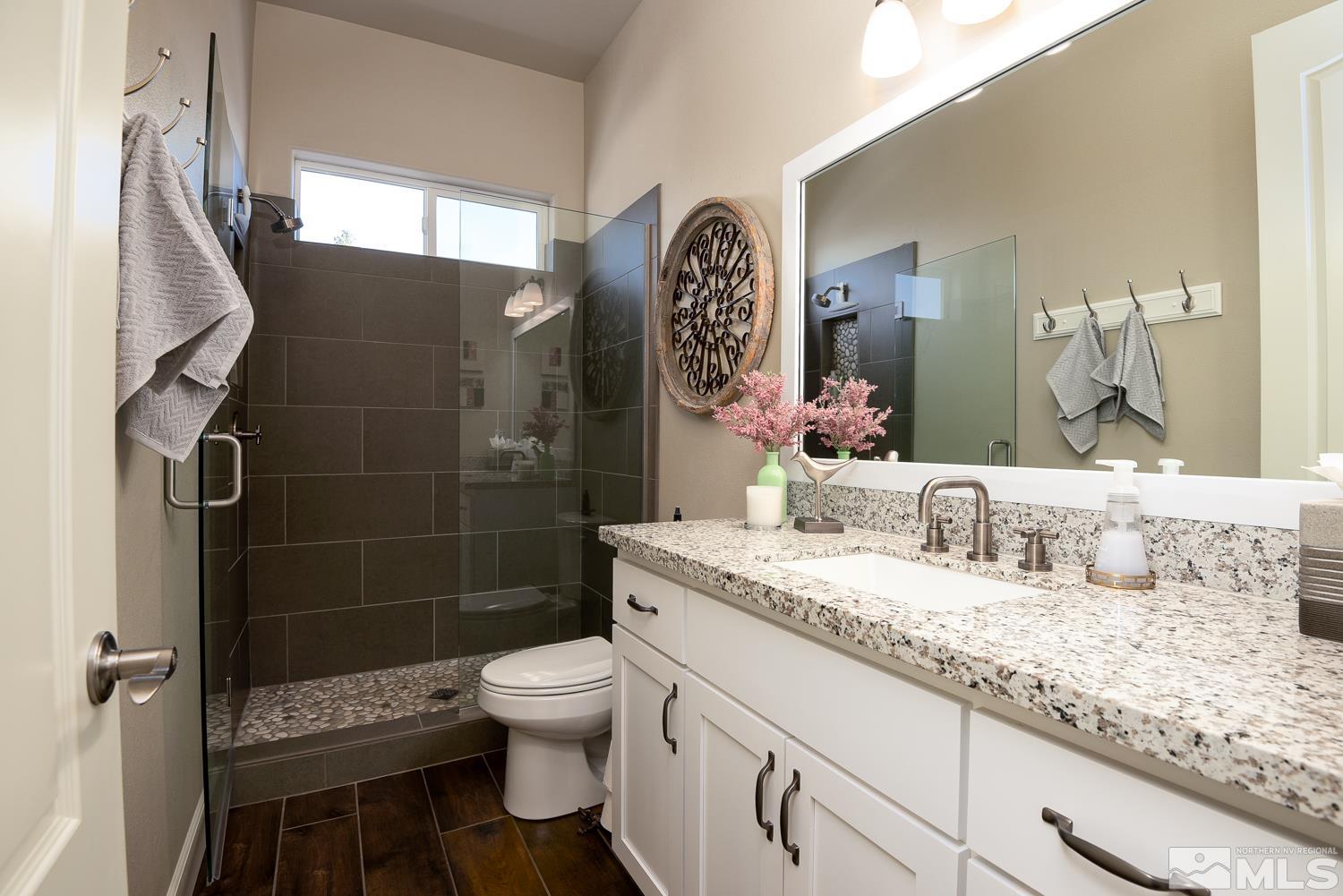 Undisclosed Address Minden, NV 89423 - Photo 19 of 33 a bathroom with a granite countertop sink a toilet a mirror and shower