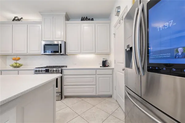 a kitchen with stainless steel appliances granite countertop a sink a stove a refrigerator a microwave and white cabinets