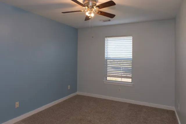 an empty room with windows and fan