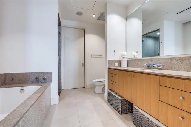 a bathroom with a granite countertop tub sink and mirror