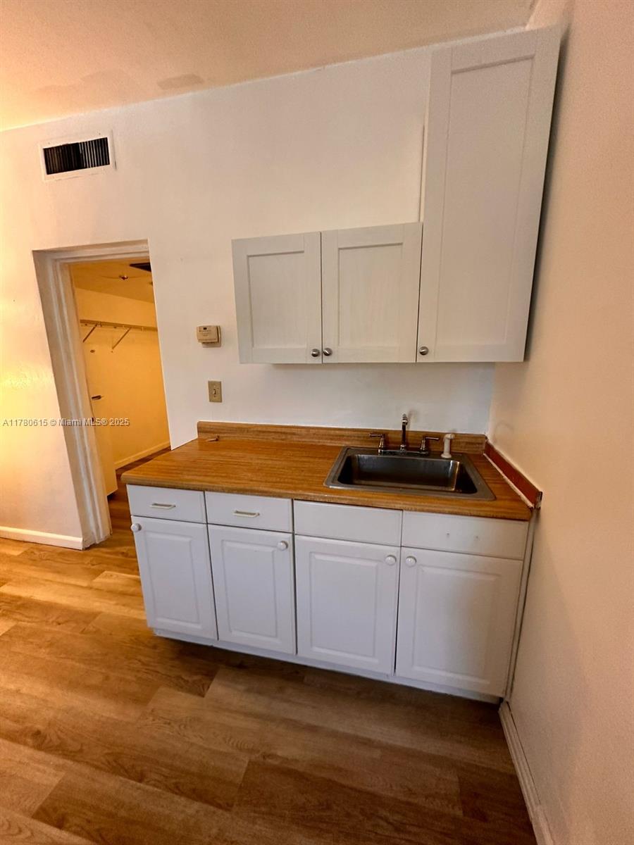 26 Diplomat Parkway, Unit 2259 Hallandale Beach, FL 33009 - Photo 6 of 10 a room with wooden floor and cabinets