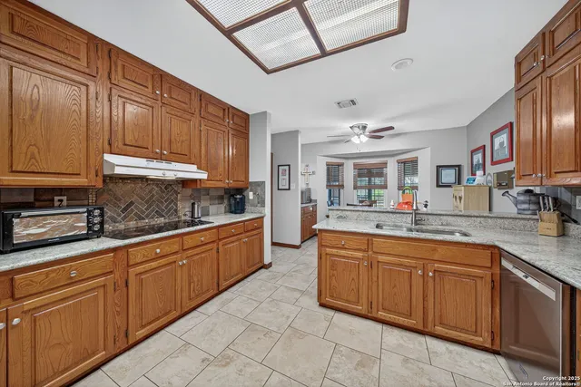 a large kitchen with kitchen island granite countertop a sink and dishwasher wooden cabinets with granite countertops