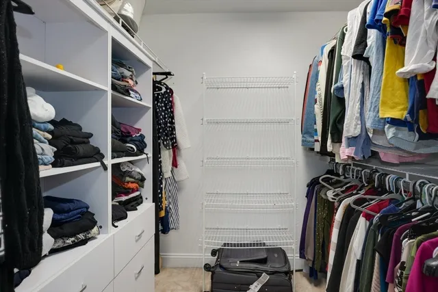 a view of walk in closet with clothes and shoes