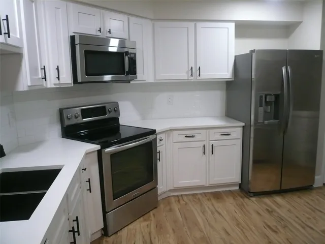 a kitchen with stainless steel appliances a stove a microwave a sink and cabinets