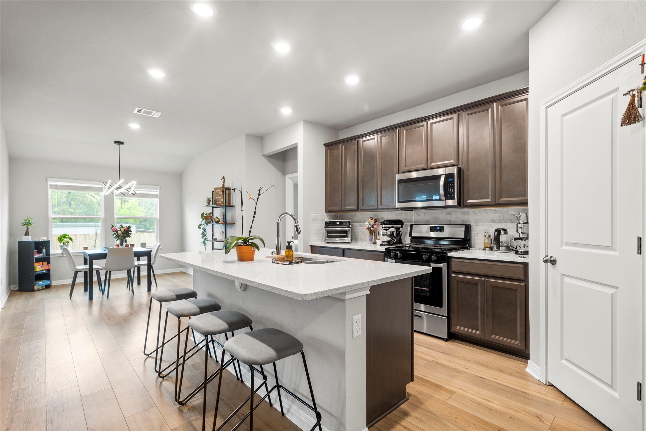 11701 Copperstone Avenue Austin, TX 78748 - Photo 4 of 29 Kitchen featuring dark wood finish cabinets, stainless steel appliances, a breakfast bar, an island with sink, and decorative backsplash