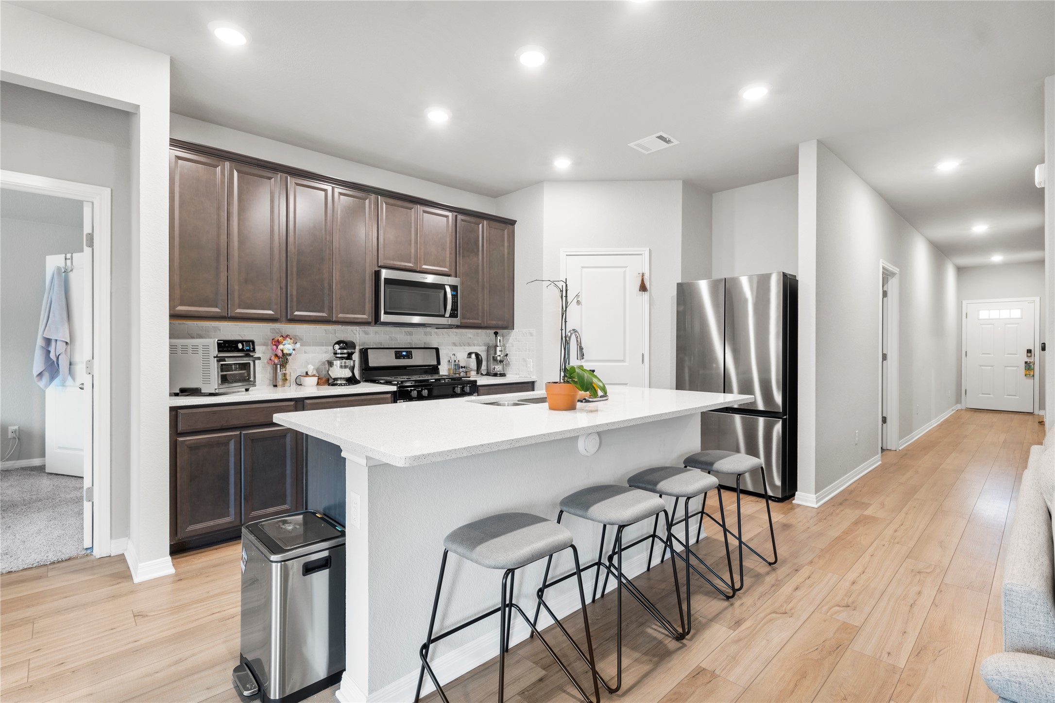 11701 Copperstone Avenue Austin, TX 78748 - Photo 5 of 29 Kitchen with recessed lighting, stainless steel appliances, dark wood finish cabinetry, a breakfast bar, and a kitchen island with sink