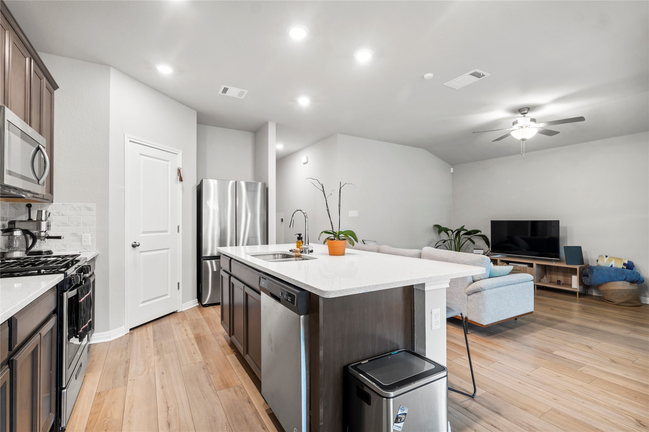 11701 Copperstone Avenue Austin, TX 78748 - Photo 6 of 29 Kitchen featuring stainless steel appliances, light stone counters, a center island with sink, a kitchen bar, and ceiling fan