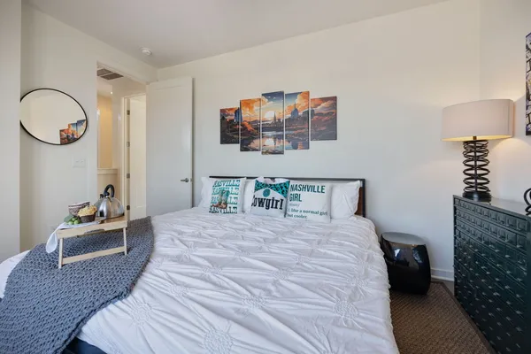 a bedroom with a bed and a lamp on dresser