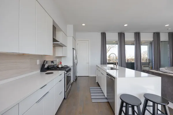 a large kitchen with stainless steel appliances granite countertop a stove a sink dishwasher and a refrigerator with wooden floor