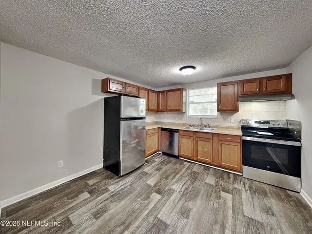 a kitchen with granite countertop a refrigerator and a stove top oven