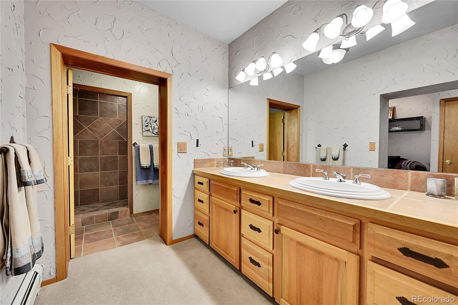 31453 Upper Bear Creek Road Evergreen, CO 80439 - Photo 13 of 22 a spacious bathroom with a double vanity sink a mirror and a shower