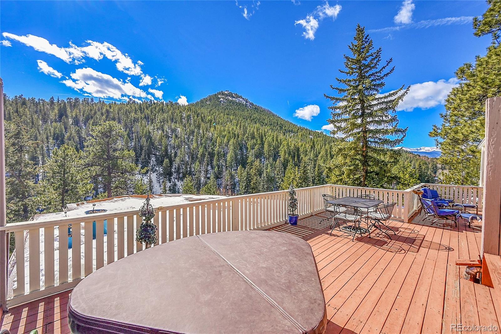 31453 Upper Bear Creek Road Evergreen, CO 80439 - Photo 16 of 22 a view of a balcony with dining table and chairs with wooden floor and fence