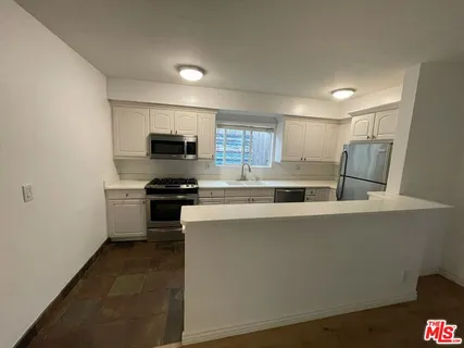 a kitchen with a refrigerator and a stove top oven