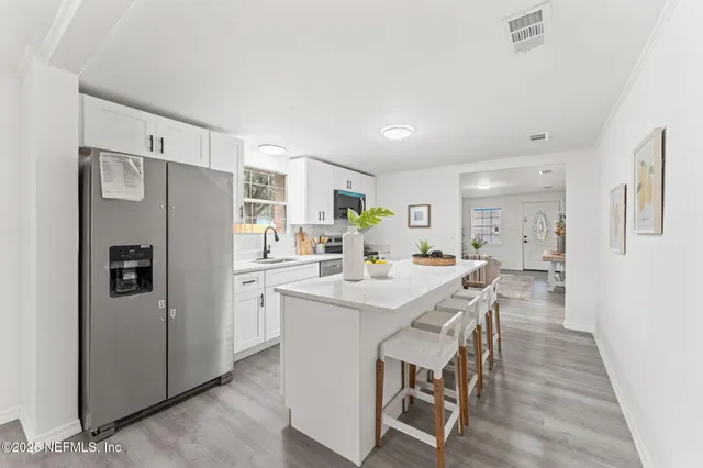 a kitchen with stainless steel appliances a refrigerator a table and chairs