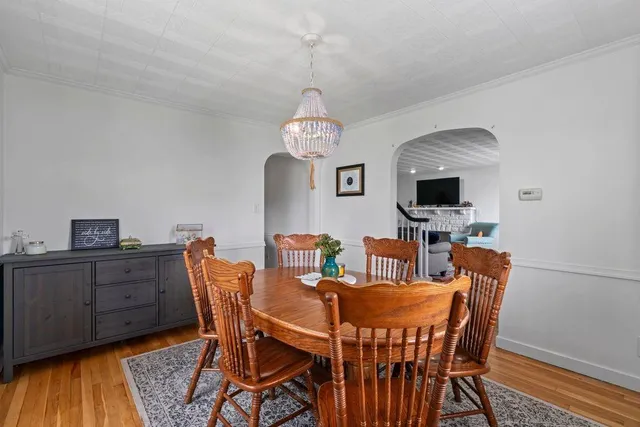 a dining room with furniture a chandelier and wooden floor
