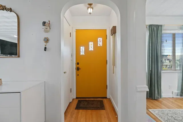 a view of a hallway with wooden floor and a livingroom