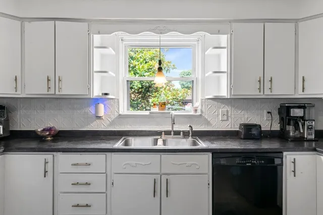 a kitchen with granite countertop white cabinets white appliances and a sink