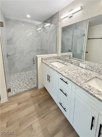 a bathroom with a granite countertop sink a large mirror and a shower