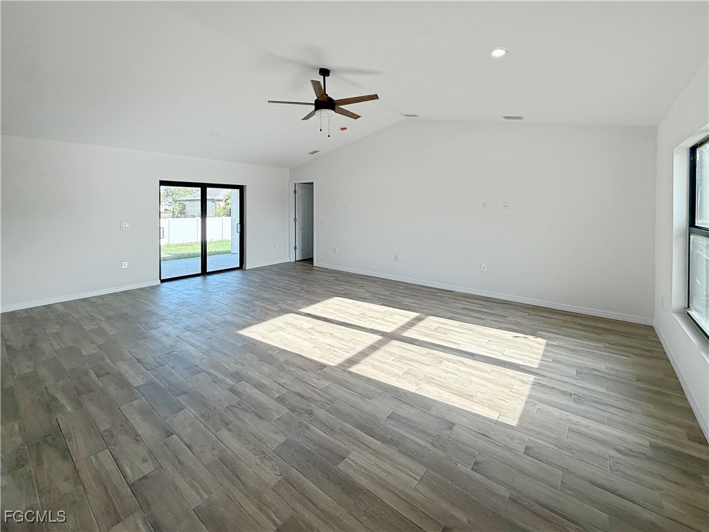 8157 Albatross Road Fort Myers, FL 33967 - Photo 3 of 24 an empty room with wooden floor chandelier fan and windows