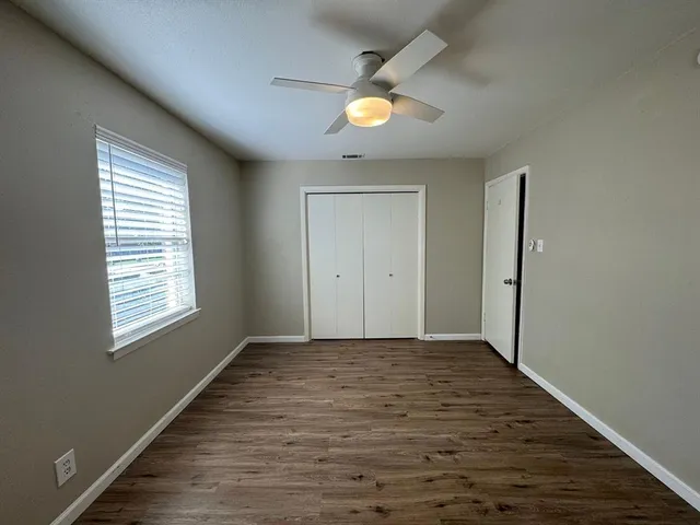 a view of an empty room with window and wooden floor