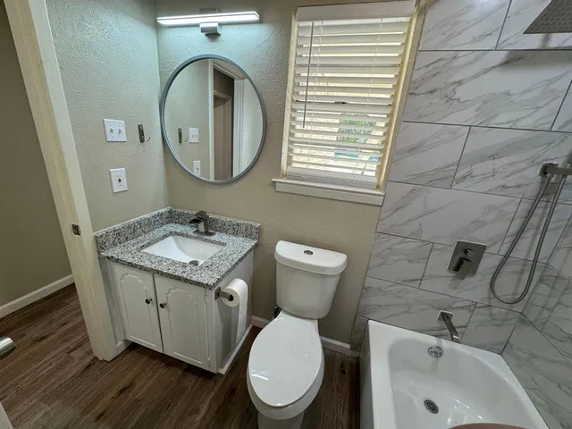 a bathroom with a granite countertop toilet a sink and a mirror