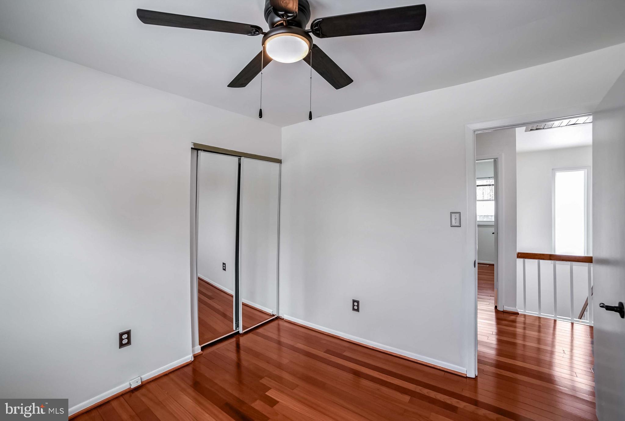 9551 Saddlebag Row Columbia, MD 21045 - Photo 15 of 30 a view of an empty room with wooden floor and a ceiling fan