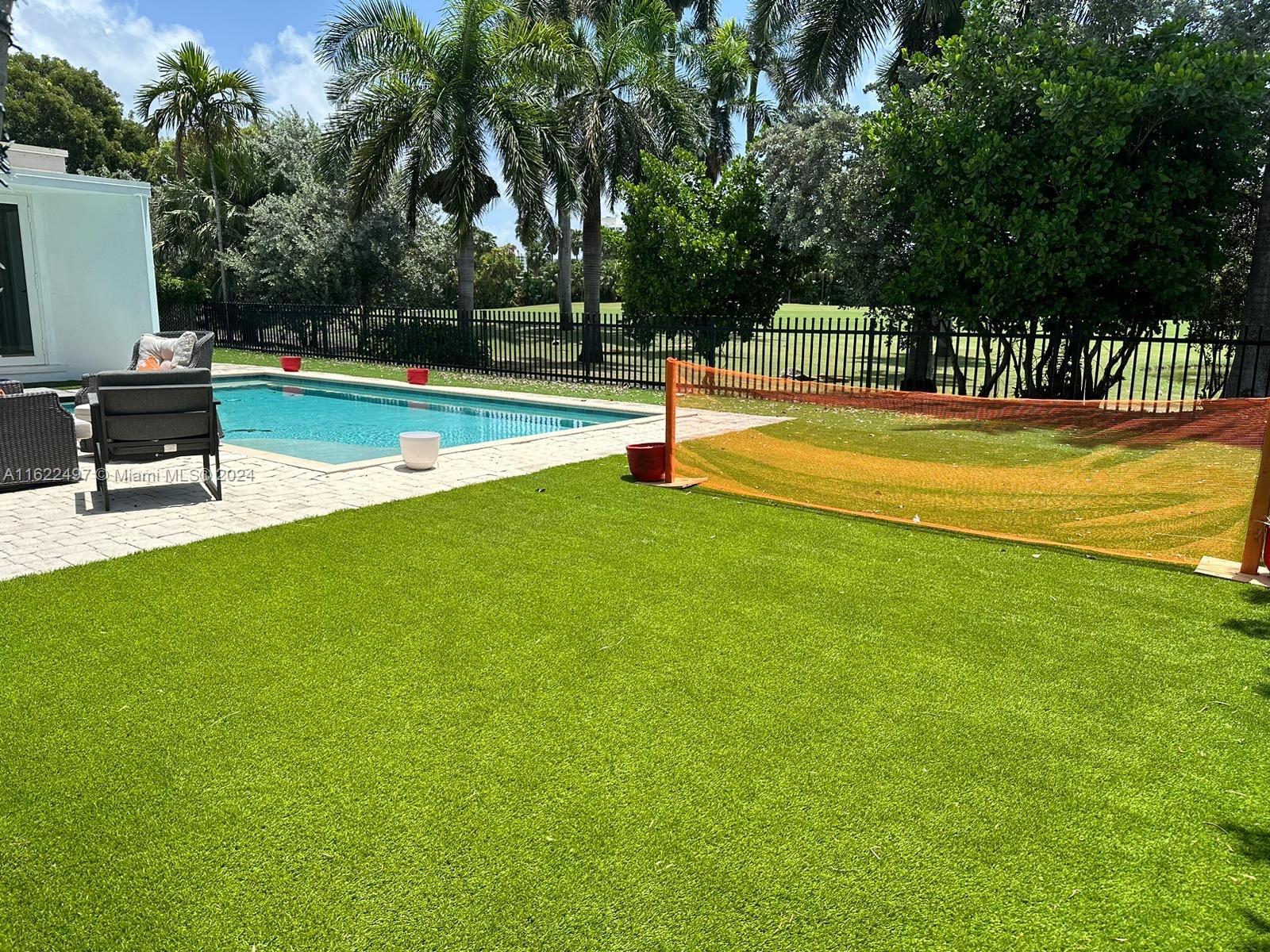5301 Alton Road Miami Beach, FL 33140 - Photo 21 of 46 a view of a swimming pool with a bench and trees around