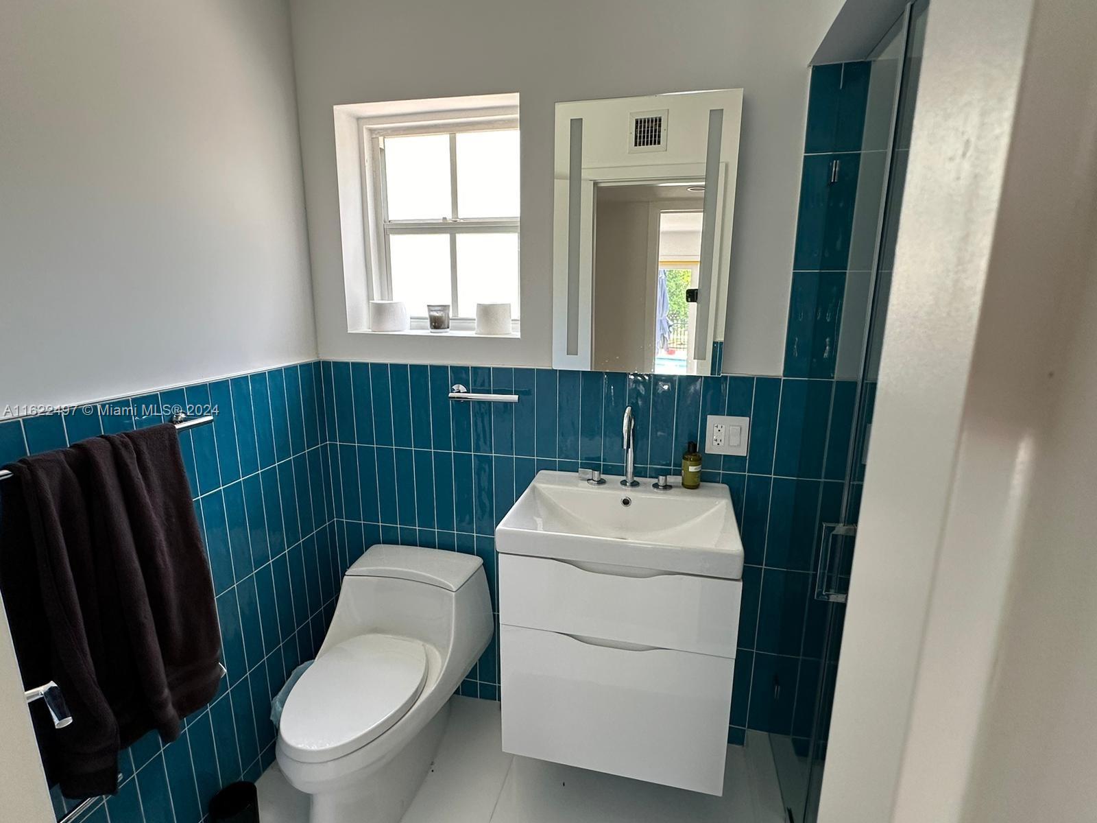 5301 Alton Road Miami Beach, FL 33140 - Photo 42 of 46 a bathroom with a toilet a sink and a mirror