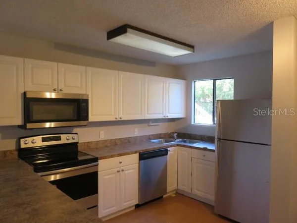 a kitchen with granite countertop a refrigerator and a stove top oven