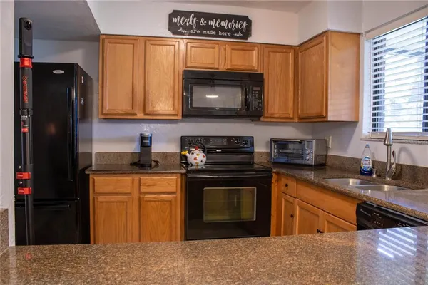 a kitchen with granite countertop stainless steel appliances white cabinets sink and a granite counter top