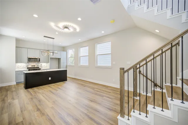 a large kitchen with stainless steel appliances kitchen island wooden floors and view living room