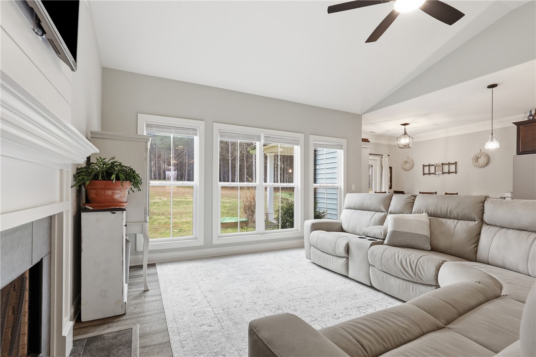 127 West Stewart Street Pelzer, SC 29669 - Photo 4 of 23 Bright and airy living area with a cozy fireplace and expansive views of the outdoors.