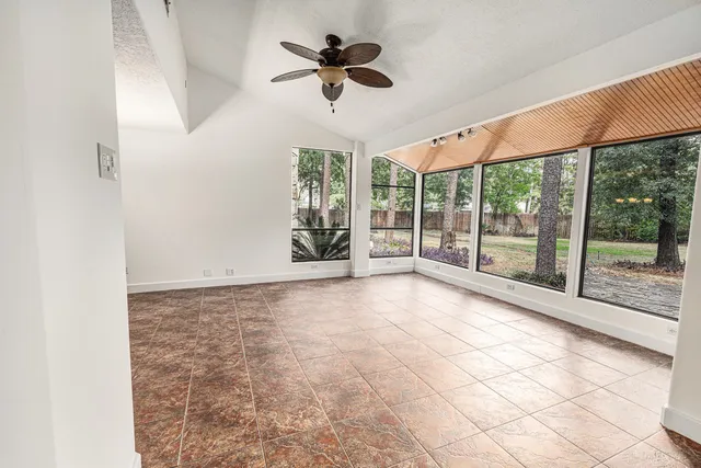 a view of an empty room with a ceiling fan and window