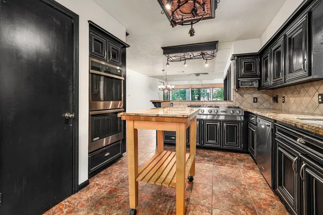 a kitchen with stainless steel appliances granite countertop a stove a sink and a refrigerator