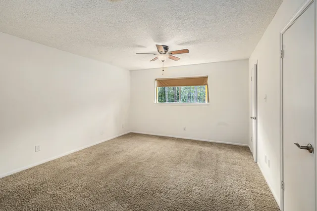 an empty room with windows and ceiling fan