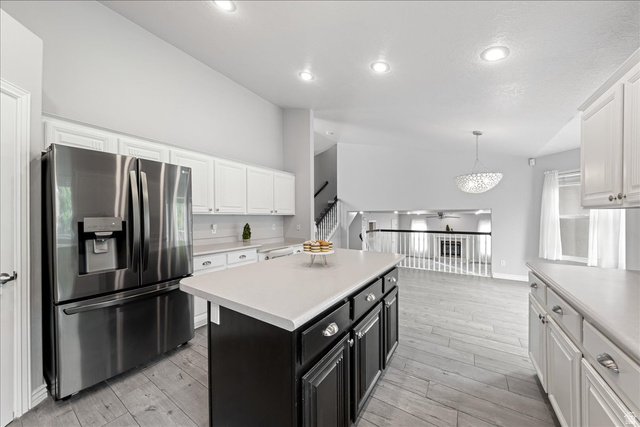 7 Reflection Way St. George, UT 84770 - Photo 31 of 54 Kitchen featuring dark cabinets, white cabinets, stainless steel fridge with ice dispenser, a kitchen island, and high vaulted ceiling