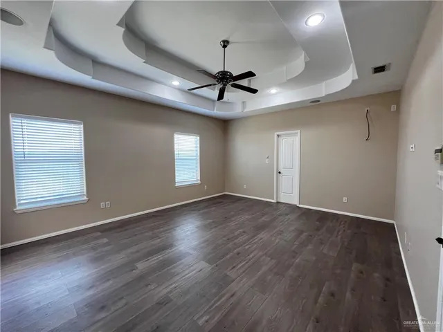 a view of an empty room with a window and wooden floor