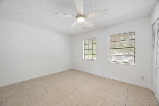 an empty room with windows and fan