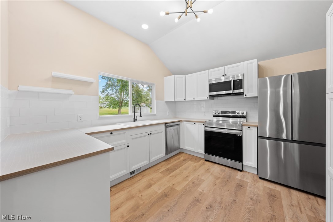 1617 Graham Road Stow, OH 44224 - Photo 21 of 49 Kitchen featuring appliances with stainless steel finishes, white cabinetry, tasteful backsplash, and light wood-type flooring
