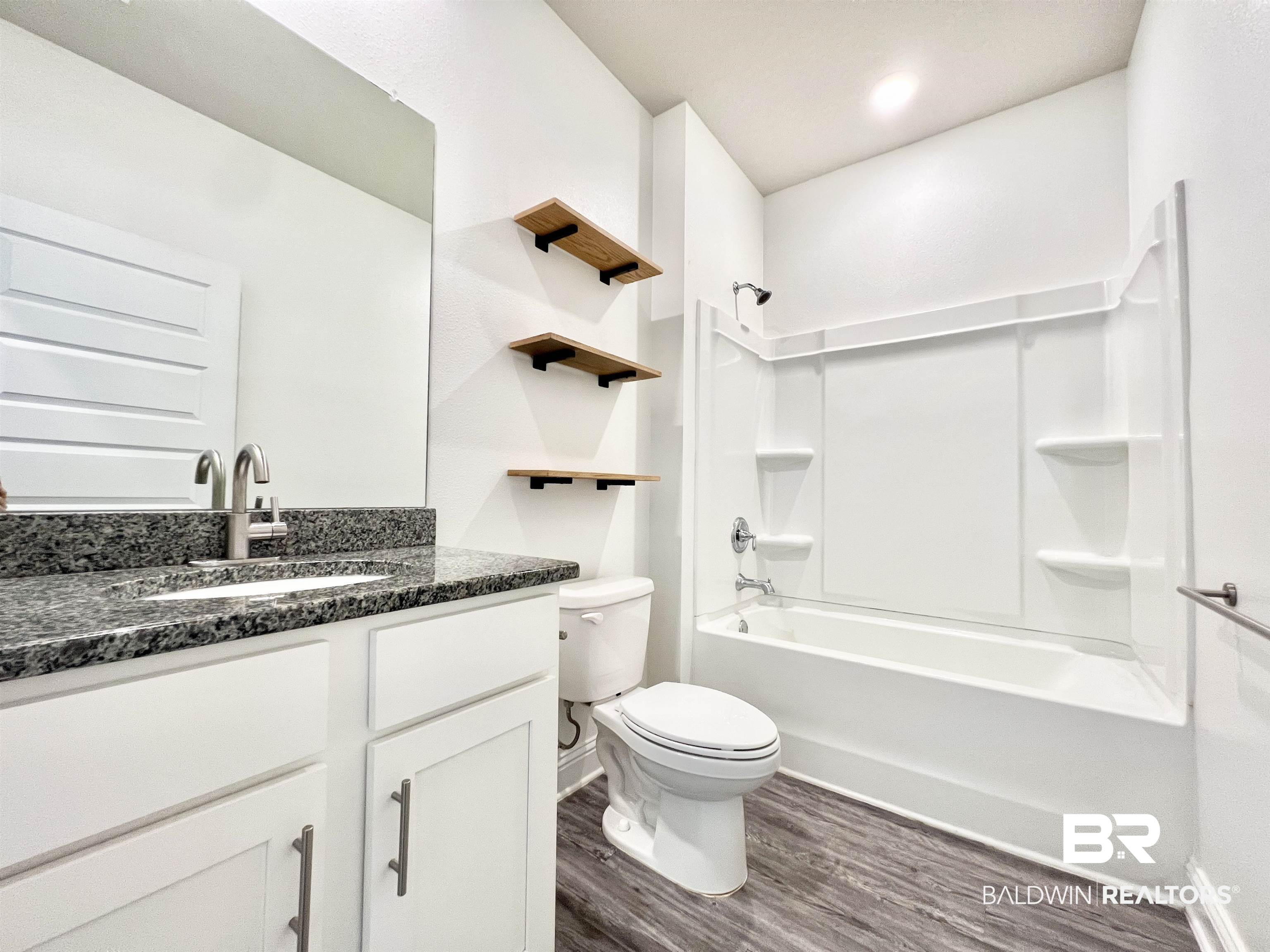 24785 Slater Mill Road Daphne, AL 36526 - Photo 16 of 46 Full bathroom with vanity, toilet, wood-type flooring, and shower / bathtub combination